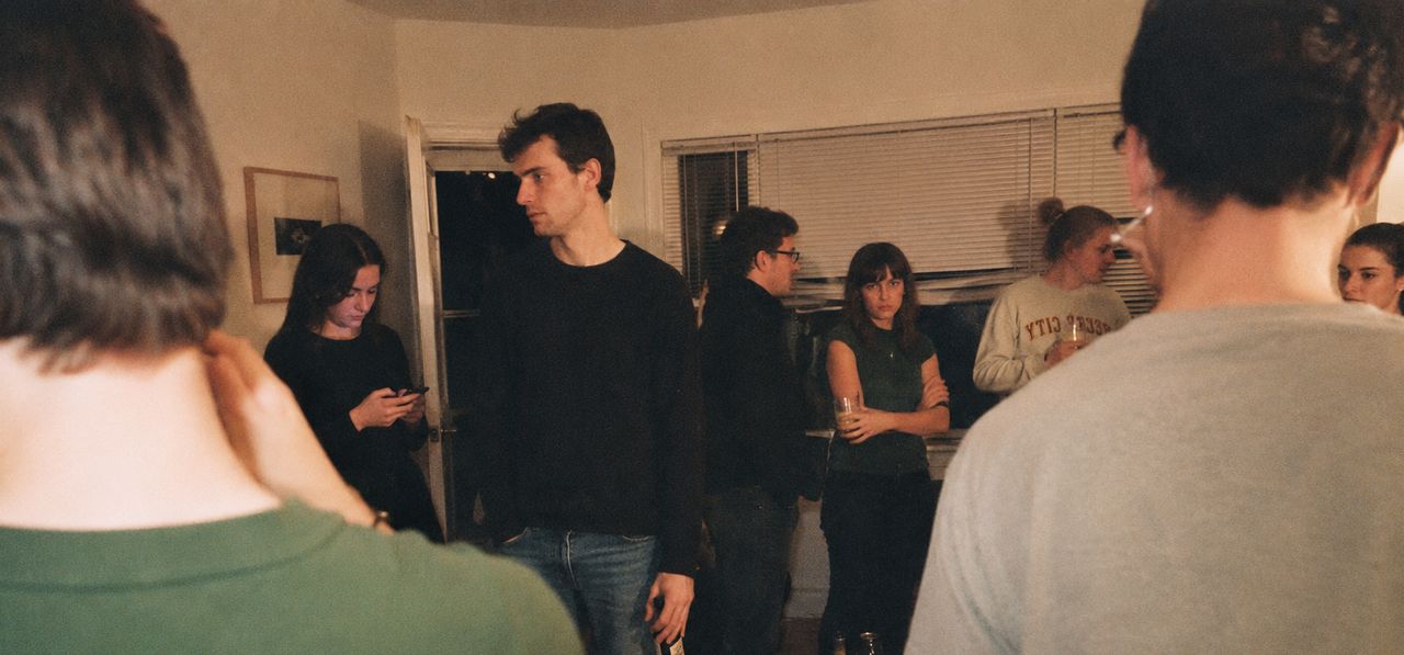 People standing around a dim, quiet living room.