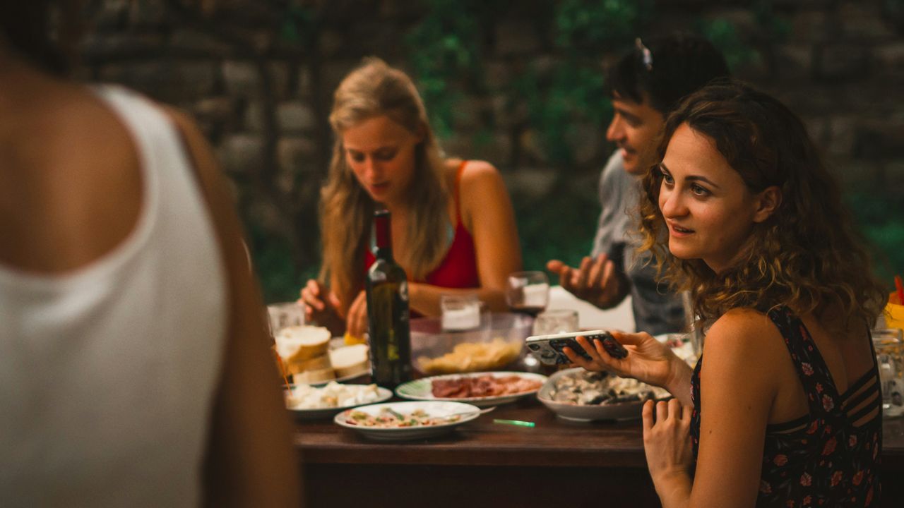 Friends gathered around a table with food and drinks.