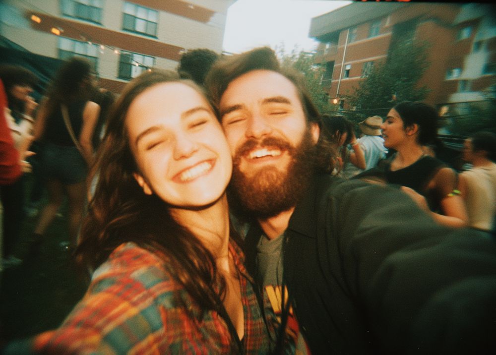 A couple grinning with their arms around each other at a party.